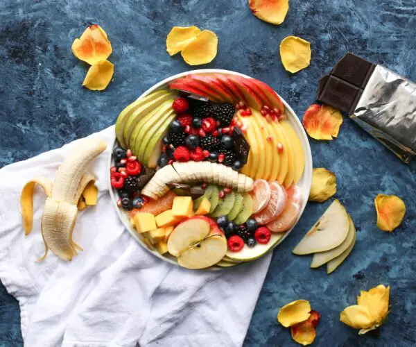 bowl of sliced fruits on white textile